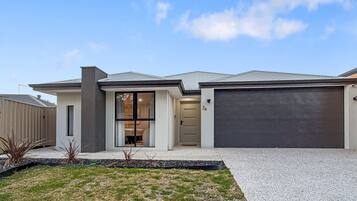 A modern two-story house with a garage, a driveway, and a well-maintained lawn.