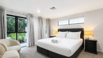 A hotel room with a large bed, two bedside tables, a chair, and a window with curtains.