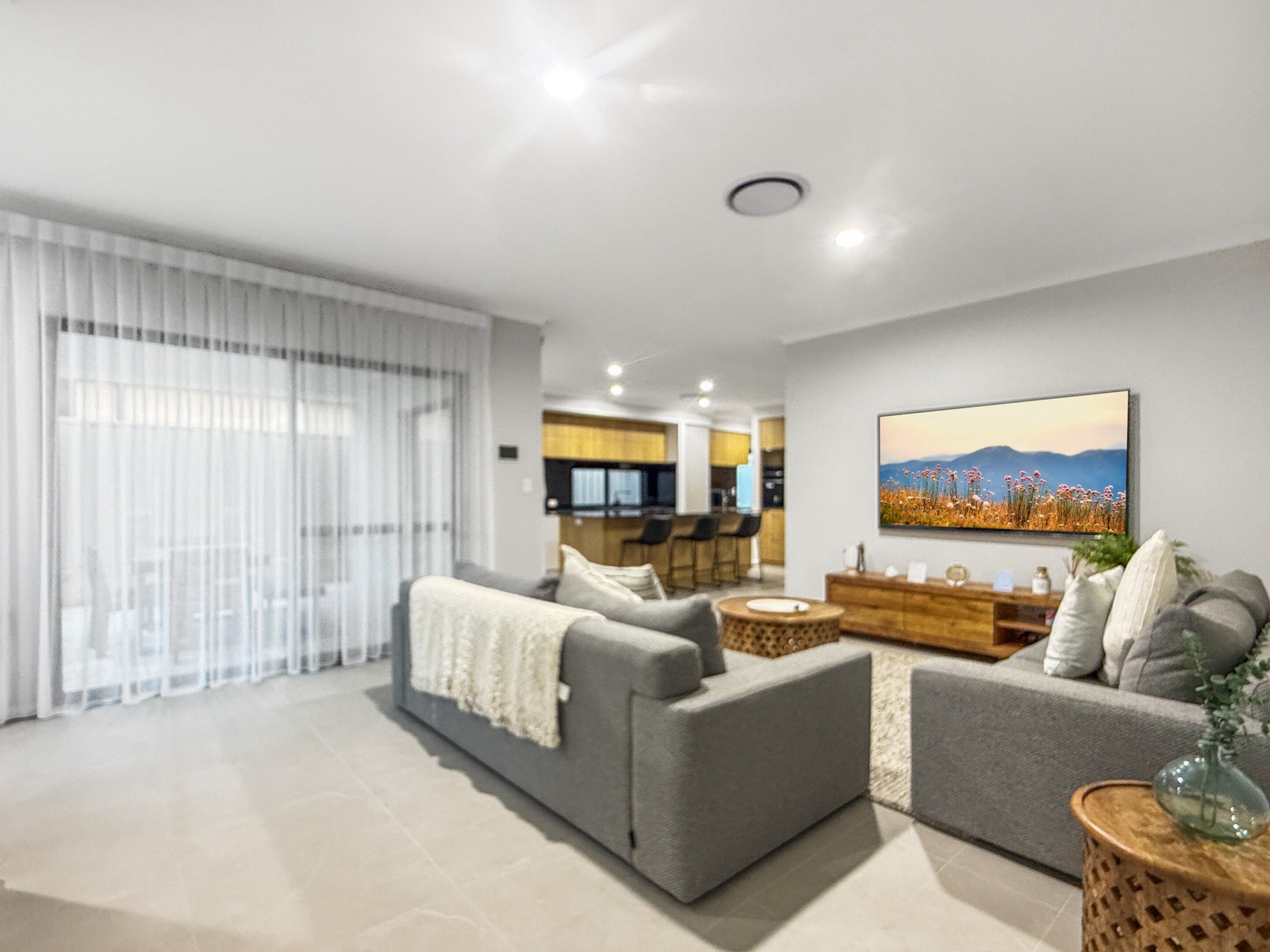A modern living room with a grey sofa set, a coffee table, and a dining area in the background.