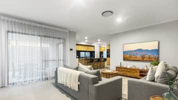 A modern living room with a grey sofa set, a coffee table, and a dining area in the background.