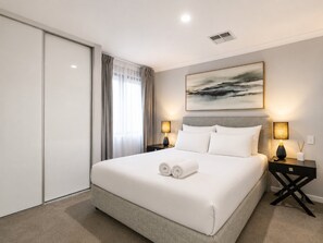 A hotel room with a large bed, two bedside tables with lamps, a painting on the wall, and a sliding door. - Spacious 4-bed Retreat Near Meadow Springs (Perth)