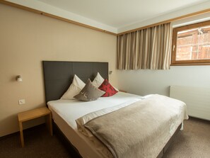 A hotel room with a bed, bedside table, and a window with curtains. - Haus am Brunnen, (Samnaun-Compatsch) by Interhome (Samnaun)