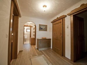 Ein Flur mit Holzboden, einer Holztür und einem kleinen Schrank mit einem Gemälde darüber.