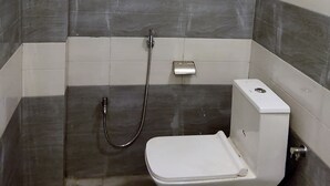 Et badeværelse med bruser, toilet og et vandhane monteret på væggen.