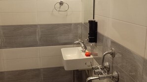 Et badeværelse med hvid vask, brusehåndbruser og håndklædestang.