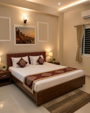 A bedroom with a large bed, two bedside tables, a nightstand, a wall-mounted air conditioner, and a window with curtains.