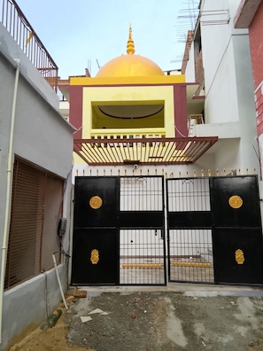 A gated entrance with a yellow and red building in the background. - Shivansi Residency (Varanasi)