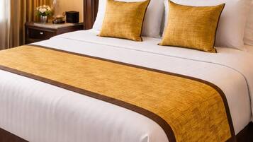 A hotel room with a large bed, a headboard, a bedside table with a lamp, and a carpeted floor.