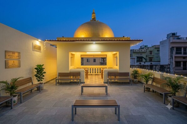 A building with a golden dome, a reception area with benches, and potted plants.