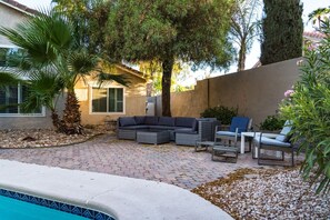 A patio with a pool, outdoor furniture, and a stone wall. - Vegas Gem Retreat w/Pool & Nearby Strip (Henderson)