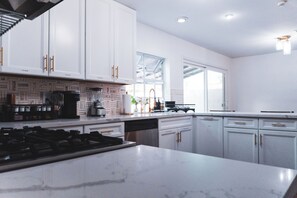 A modern kitchen with white cabinetry, a marble countertop, and a gas stove. - Vegas Gem Retreat w/Pool & Nearby Strip (Henderson)