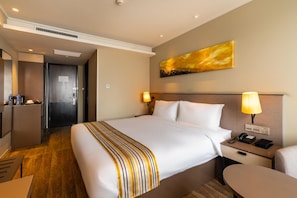 Ein Hotelzimmer mit Bett, Nachttisch, Lampe und einem Bild an der Wand.