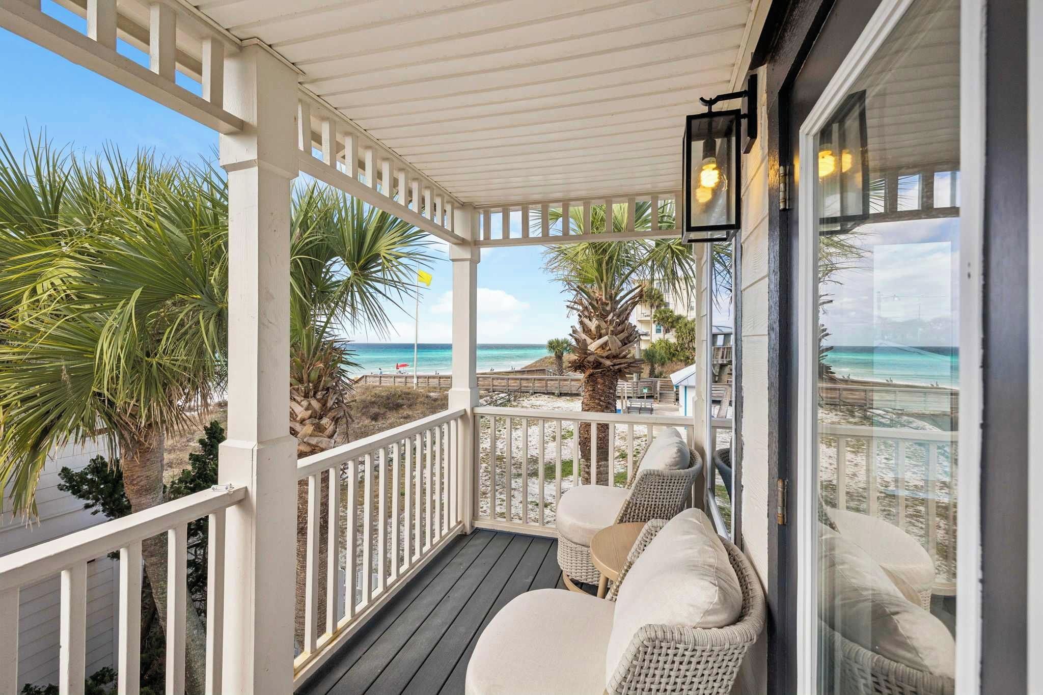 A covered outdoor seating area with wicker furniture and a view of the beach.