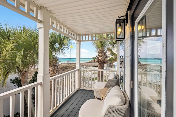Un espace extérieur abrité, aménagé avec des meubles en osier et offrant une vue sur la plage.