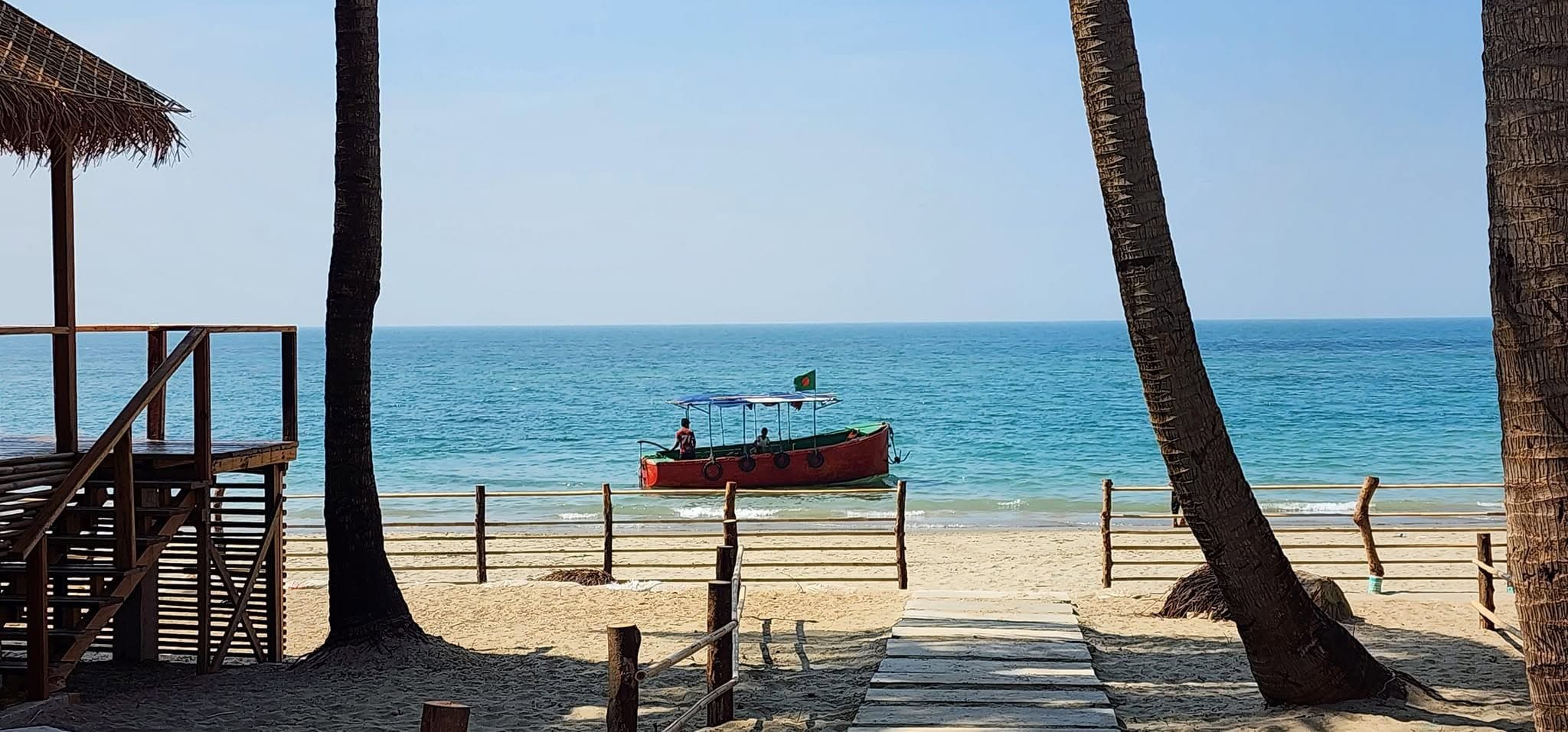 Una spiaggia con una passerella in legno che conduce a una barca ormeggiata sulla sabbia.