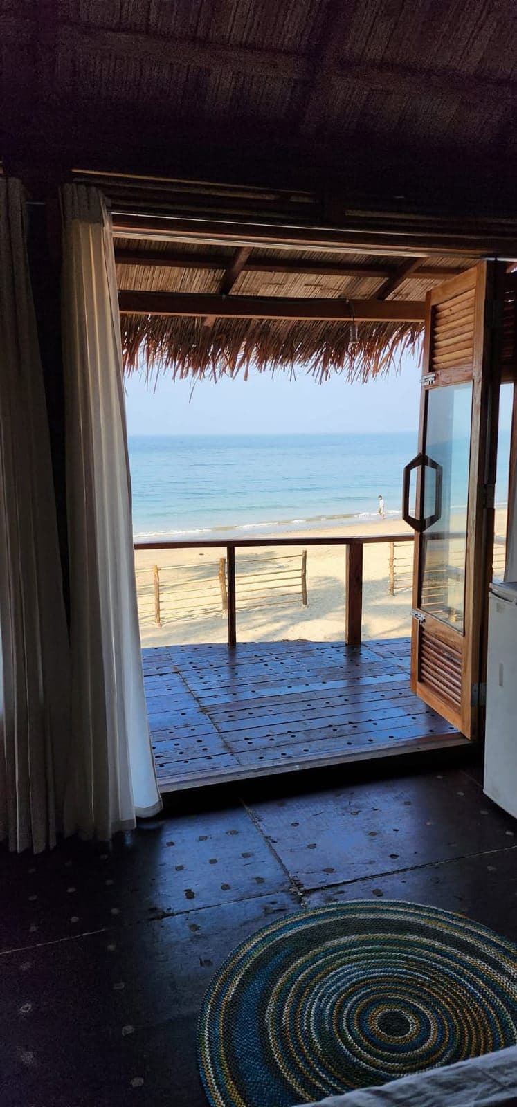 Ein Zimmer mit Blick auf den Strand, einer Holztür und einem Reetdach.