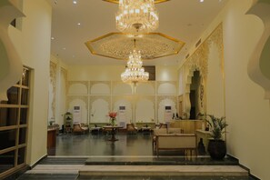 Un'ampia hall con un maestoso lampadario, decorazioni murali elaborate e una reception.