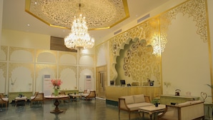 A lobby with ornate gold detailing, a chandelier, and seating arrangements. - Beelwa Palace  (Jaipur)