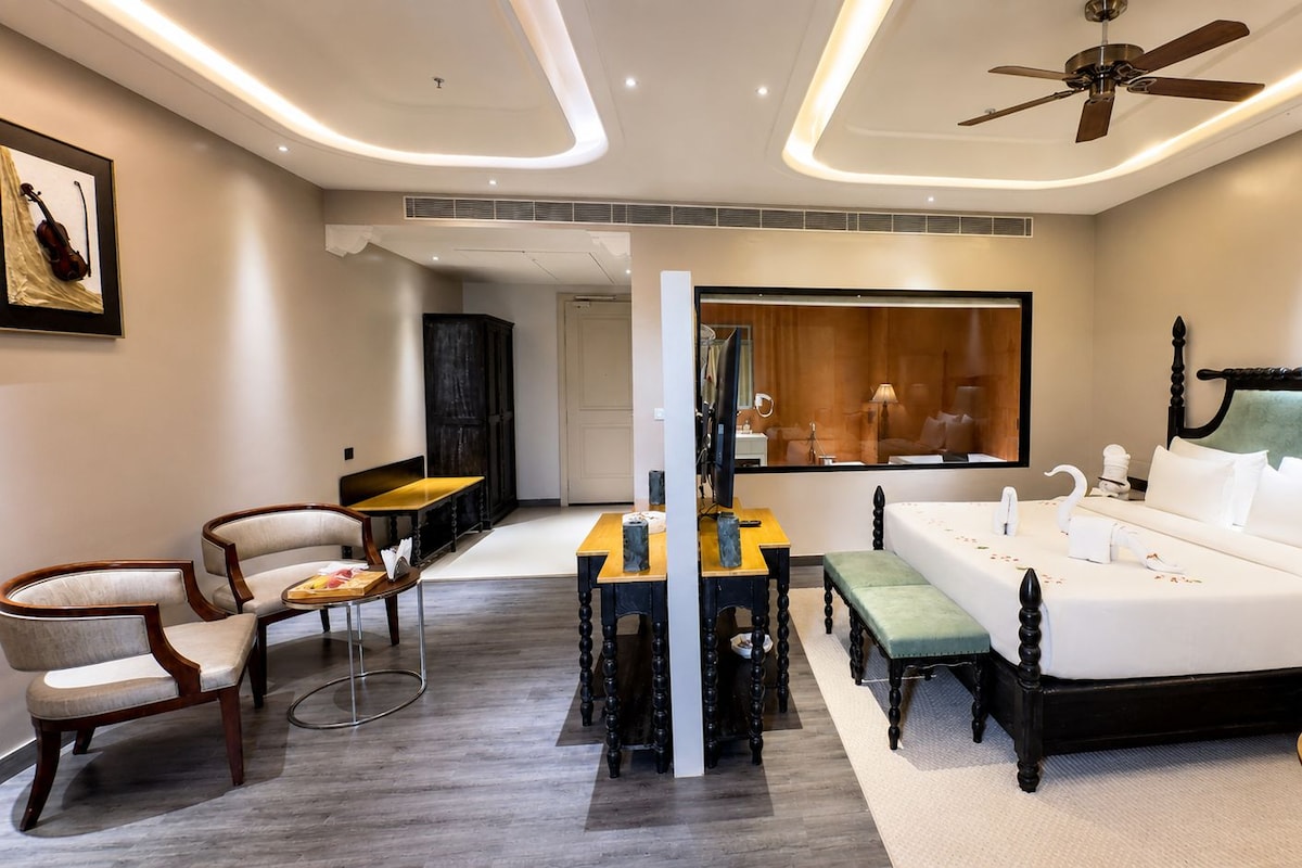 Una habitación de hotel con cama, mesitas de noche, escritorio, sillas y espejo.