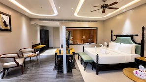 Una habitación de hotel con cama, mesitas de noche, escritorio, sillas y espejo.