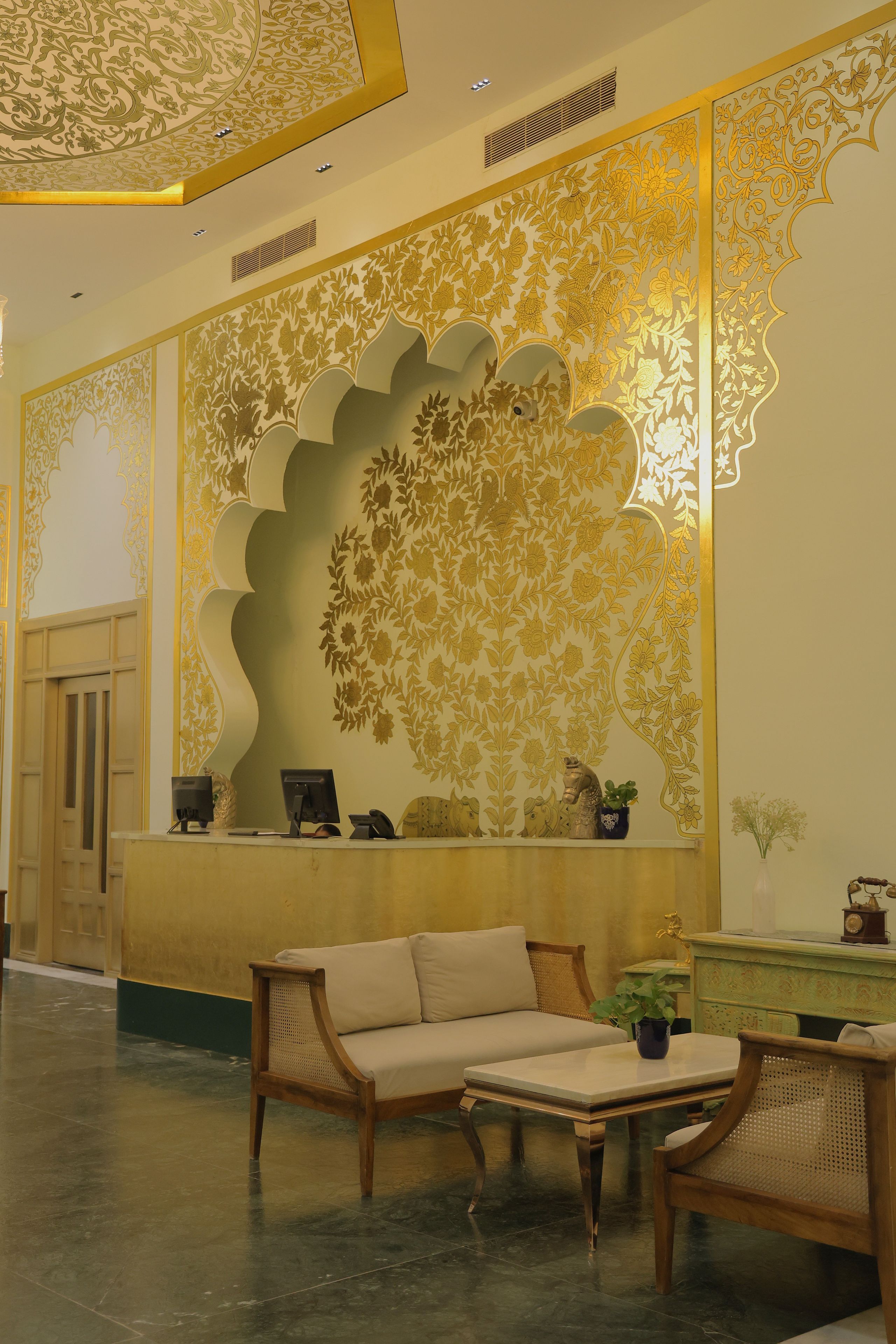 Un área de recepción con un muro decorativo, una mesa de recepción, un sofá y una mesita de café.