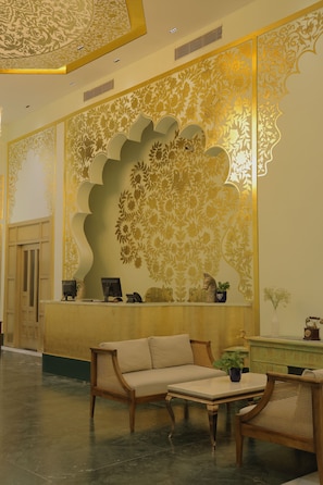 Un área de recepción con un muro decorativo, una mesa de recepción, un sofá y una mesita de café.