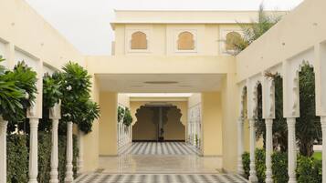 A courtyard with a checkered floor, white columns, and a central entrance with a decorative archway.