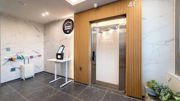 A hotel reception area with a marble wall, a wooden panel, a reception desk, and a luggage trolley.