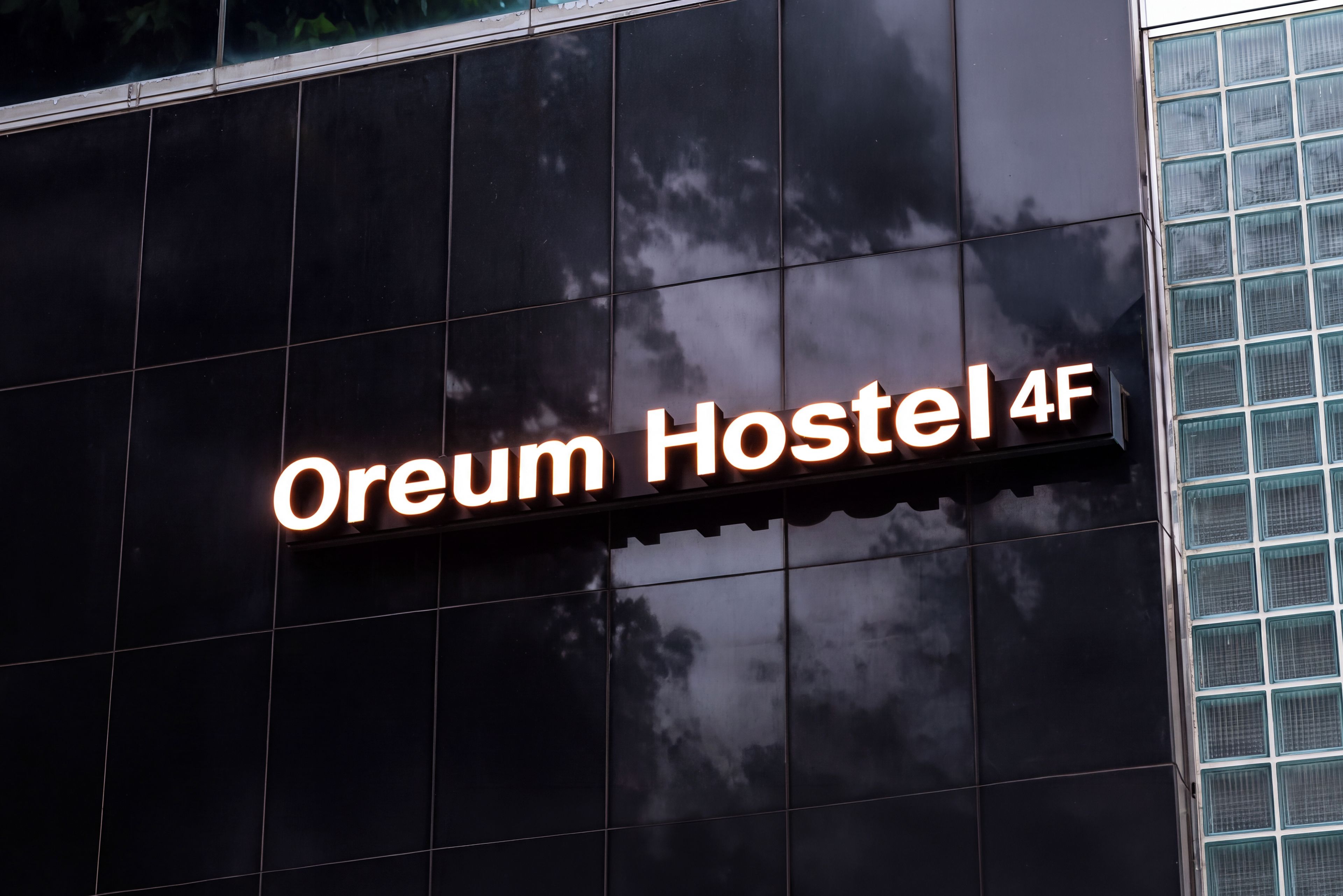 A sign for 'Oream Hostel 4F' on a building facade.