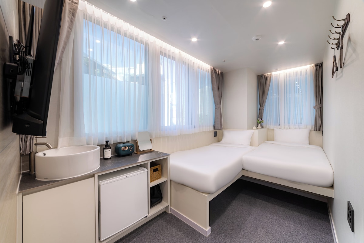 Une chambre d’hôtel avec un lit, un petit bureau doté d’un lavabo et un miroir.