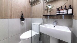 Un baño moderno con inodoro, lavamanos y ducha.