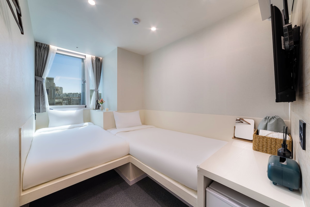 Une chambre d’hôtel avec un lit, un bureau, une télévision et une fenêtre avec des rideaux.