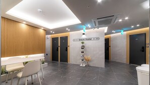 Un moderno vestíbulo de hotel con una recepción, zona de estar y señalización hacia las habitaciones 411 y 410.