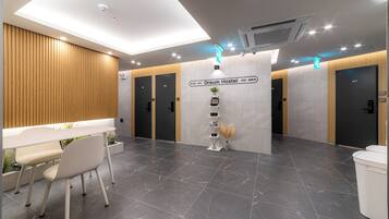 A modern hotel lobby with a reception desk, seating area, and directional signs to rooms 411 and 410.