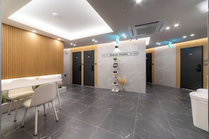 Un hall d’hôtel moderne comprenant un comptoir d’accueil, un espace salon et des panneaux indicateurs pour les chambres 411 et 410.