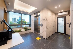 A modern elevator with a digital display, a clear path marked on the floor, and a view of the city through large windows.