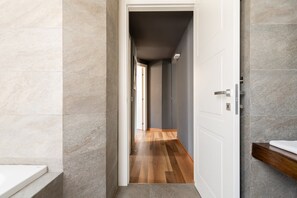 A hallway with a wooden floor, a white door, and a bathroom with a white sink and a wooden countertop. - 2 bedroom, 2 bathroom Apt + AC + FREE Garage (Milano)