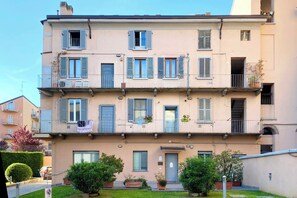 A multi-story residential building with balconies, a door, and potted plants. - 2 bedroom, 2 bathroom Apt + AC + FREE Garage (Milano)