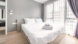 Une chambre d’hôtel moderne avec un grand lit, une table de chevet, un miroir et une fenêtre avec des rideaux.