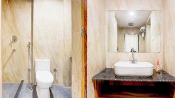 A bathroom with a toilet, a shower, and a sink with a mirror above it.