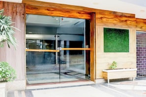 A building entrance with a glass door, a wooden frame, and a bench outside. - Townhouse Oak Dhanbad Near SSLNT College (Dhanbad)