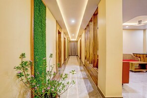 A hotel hallway with a green vertical garden, wooden doors, and a seating area with a red cushion. - Townhouse Oak Dhanbad Near SSLNT College (Dhanbad)