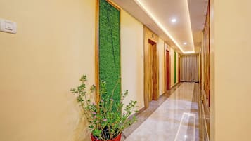 A hotel hallway with a green vertical garden, wooden doors, and a marble floor.