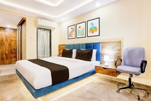 Una habitación de hotel con cama, escritorio, silla y obras de arte en la pared.