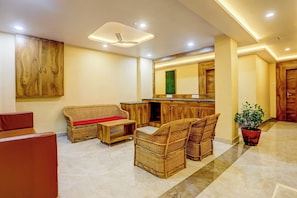 A modern interior with a sofa, wicker chairs, a kitchen area, and a wooden cabinet.