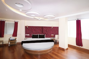 A modern bedroom with a circular bed, a tufted headboard, and a wooden floor. - Super Townhouse Bank More Dhanbad (Dhanbad)