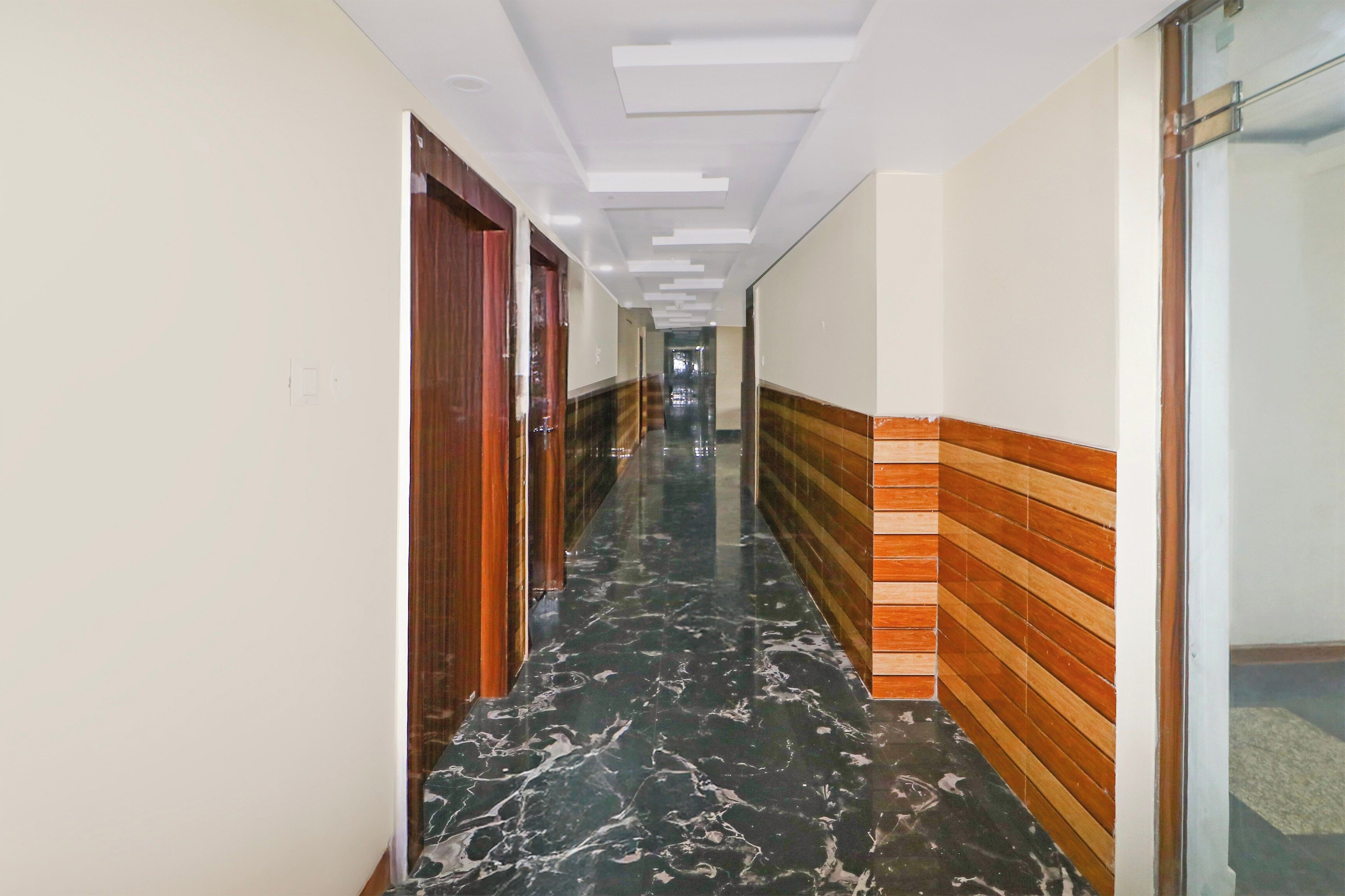 Un corridoio con pavimento in marmo, porte in legno e parete decorata.