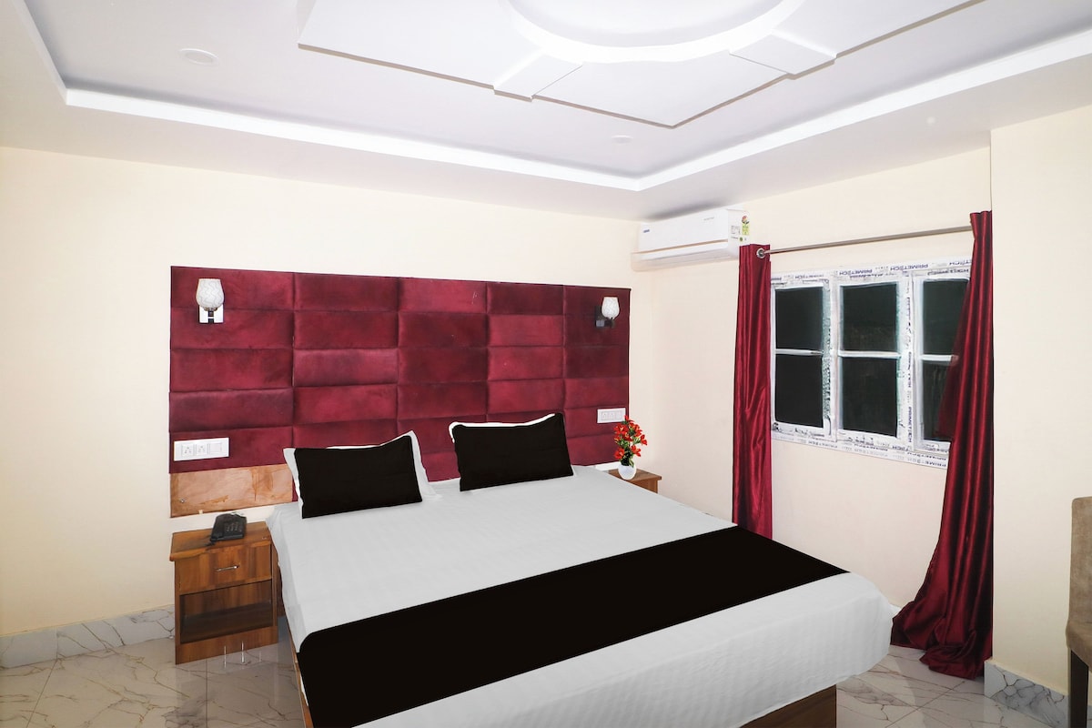 Un dormitorio con cama, mesita de noche, ventana con cortinas y aire acondicionado instalado en la pared.
