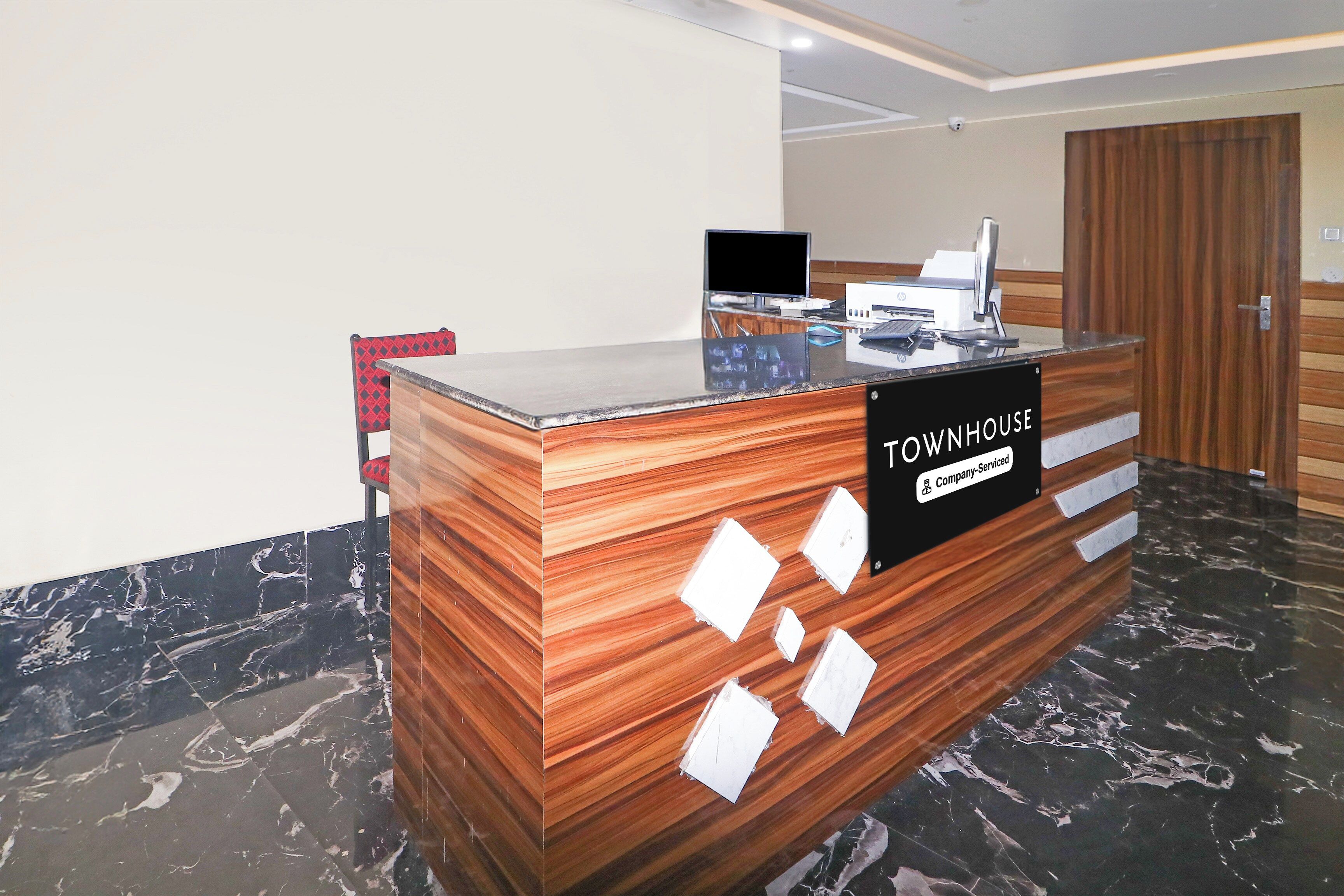 A reception desk with a sign indicating it is company-serviced, a computer, and a wooden panel design.