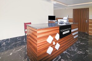 Una recepción con un cartel que indica servicio de empresa, una computadora y diseño de paneles de madera.